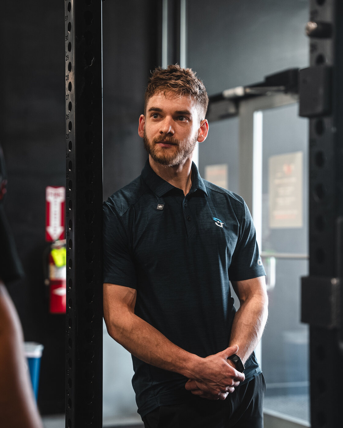 Dr. Julian Burd, PT, DPT, leaning on a squat rack at PWRBLD